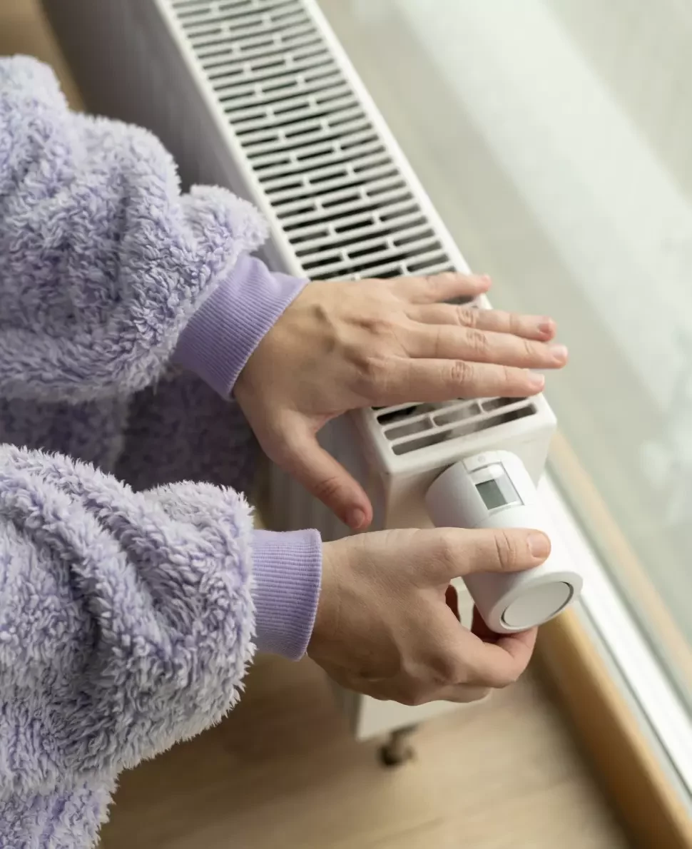 Someone puts their hand over a radiator and turns the valve on the side to detect the heat.