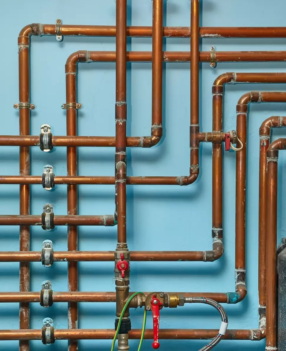 Copper piping criss-crosses against a blue wall.
